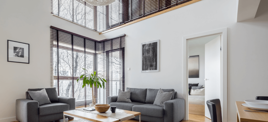 Aluminum Venetian blinds in a spacious living room with modern windows offer a perfect blend of functionality and sophistication. Their sleek, metallic finish complements the contemporary design of the windows