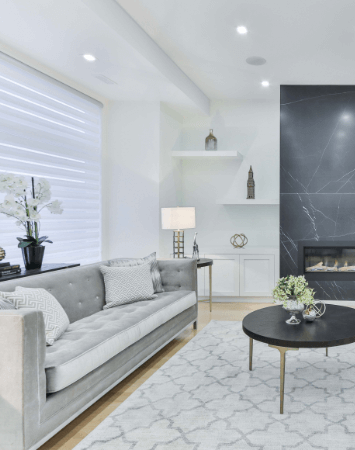 Modern living room featuring layered shades on a large window. The alternating stripes of sheer and opaque fabric offer customizable light control, with some stripes open for diffused light and others closed for privacy.