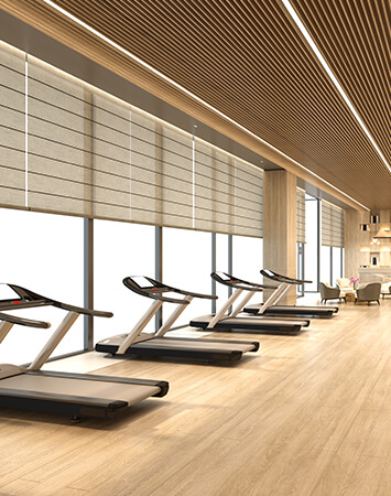 Bright gym with large windows covered in solar shades for heat control.