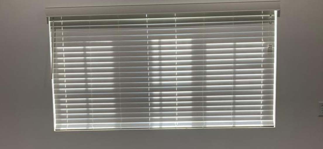 Closed aluminum blinds on a window in a modern office space