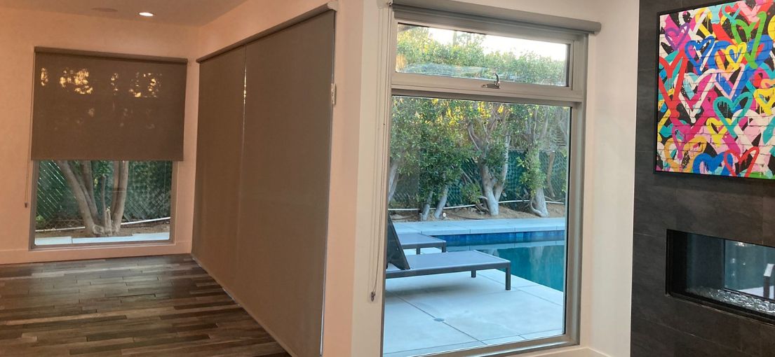 Living room space with glass walls adorned with elegant roller shades by Master Blinds.