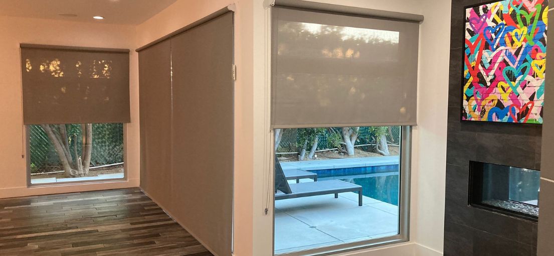 Living room space with glass walls adorned with elegant roller shades by Master Blinds.