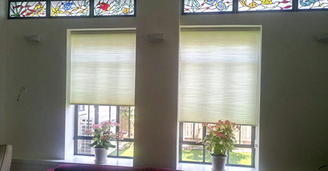 A view to a two identical windows covered with cellular shades