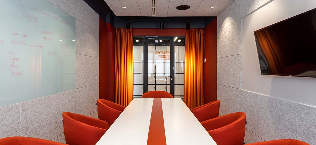 A conference room with heavy orange drapery on a glass door