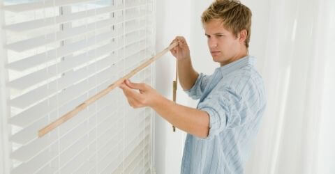 A man is measuring window for blinds installation