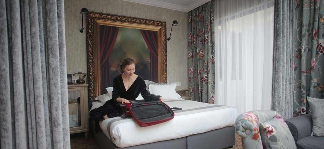 A woman with a suitcase in a hotel room
