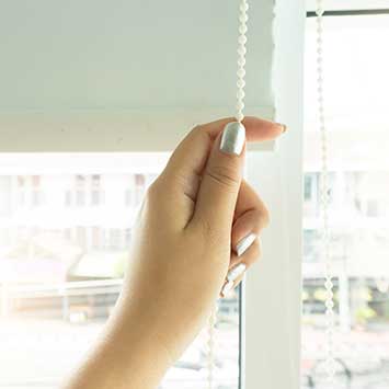A female hand holds a cord for blackout blinds