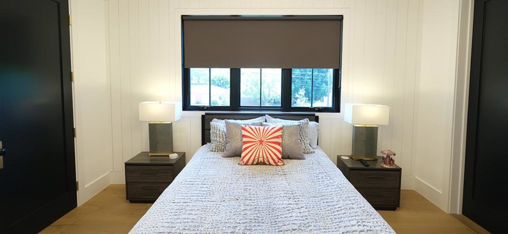 A view on a bedroom with half opened brown blackout shades