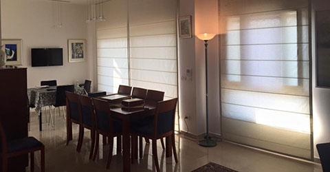 A view at dining room with motorized Roman window shading system