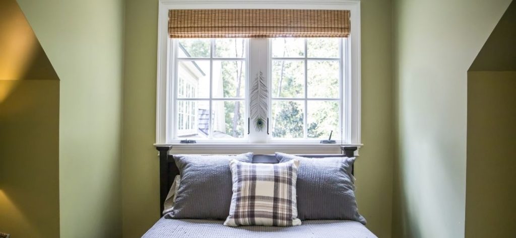 A view to a single bed bedroom with Roman shades on a window