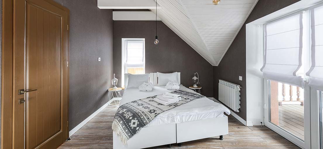A modern attic bedroom with white Roman window shades