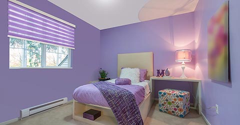 A view at a purple bedroom with layered shades