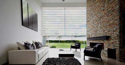 A view to a modern living room with white layered shades on a glass wall
