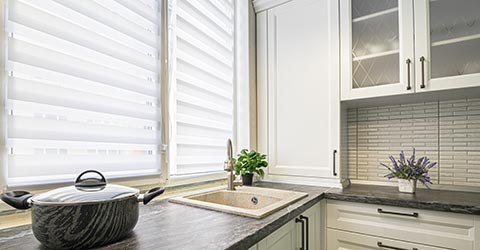 A close view at a kitchen sink and a white layered shades on a window