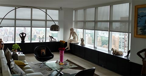 A view at a large living room with large windows covered with roller shades