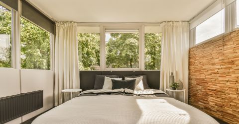 Elegant window treatments in a sunlit guest house studio with a comfortable master bed.